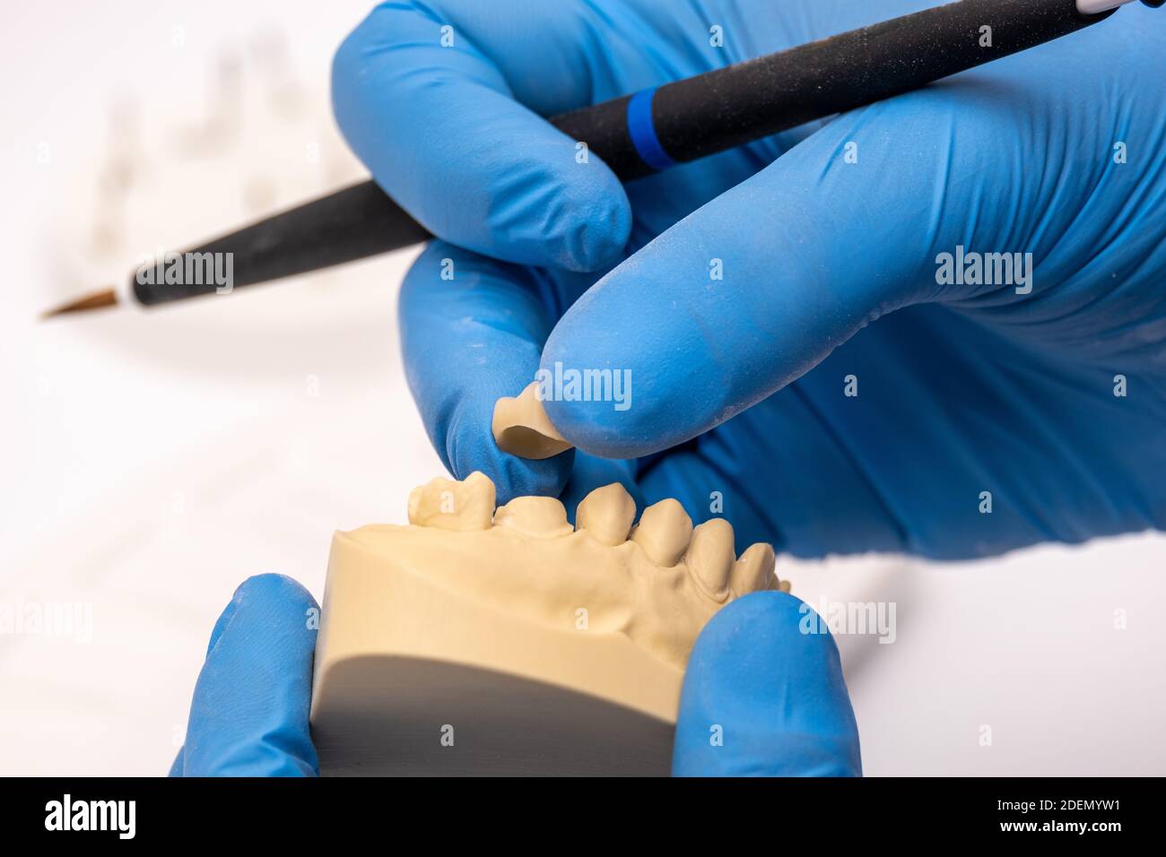 Dentista che utilizza una spazzola con impianti dentali in ceramica nel suo laboratorio. Foto Stock