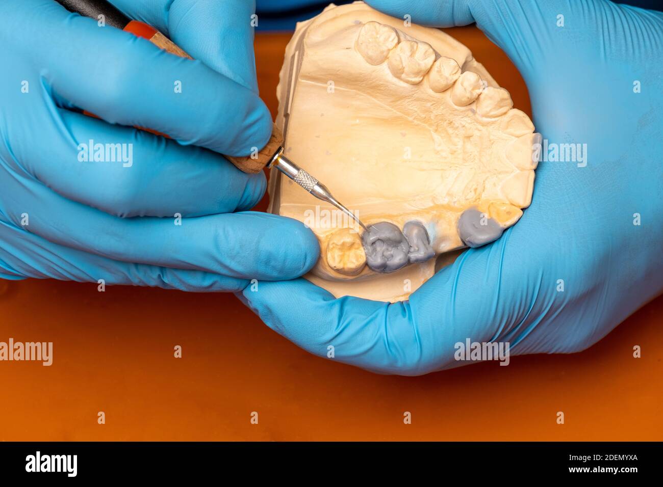 Dentista che utilizza una spazzola con impianti dentali in ceramica nel suo laboratorio. Foto Stock