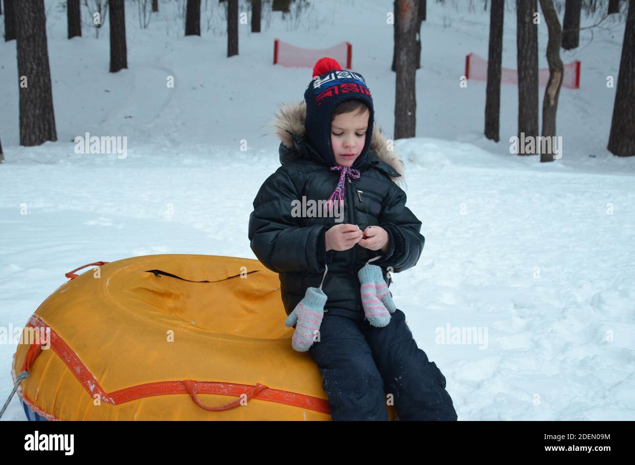Allegro bello ragazzo a cavallo di un roller coaster. Il Toddler passeggiate nella neve in inverno. Il bambino ride e sorride in winter park. Foto Stock