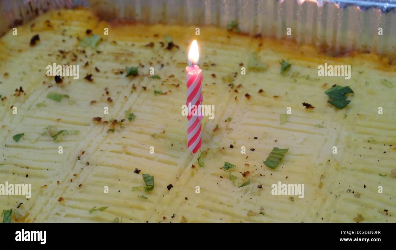 Una candela di compleanno incandescente su una torta del pastore. Foto Stock