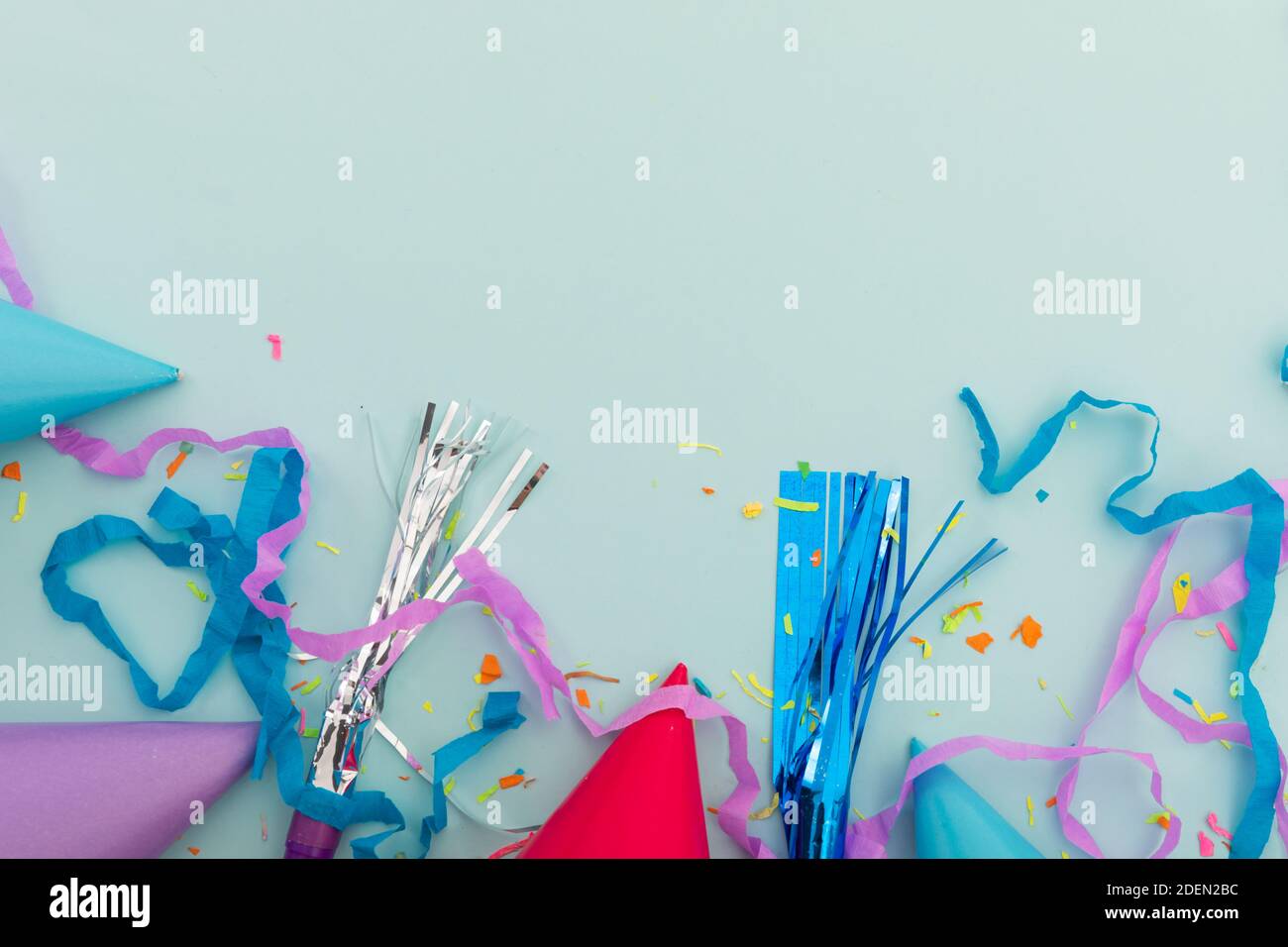 Cappello da festa, soffiatori da festa e confetti su sfondo blu Foto Stock