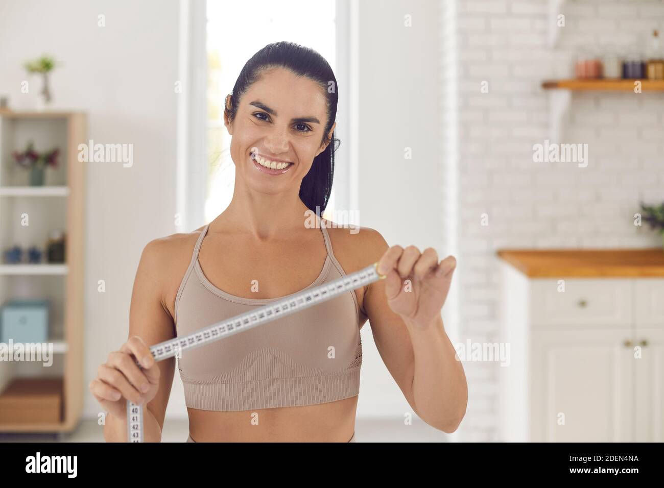 Perdita di peso allenatore che tiene metro a nastro, sorridente e motivante a rendere il vostro corpo perfetto Foto Stock