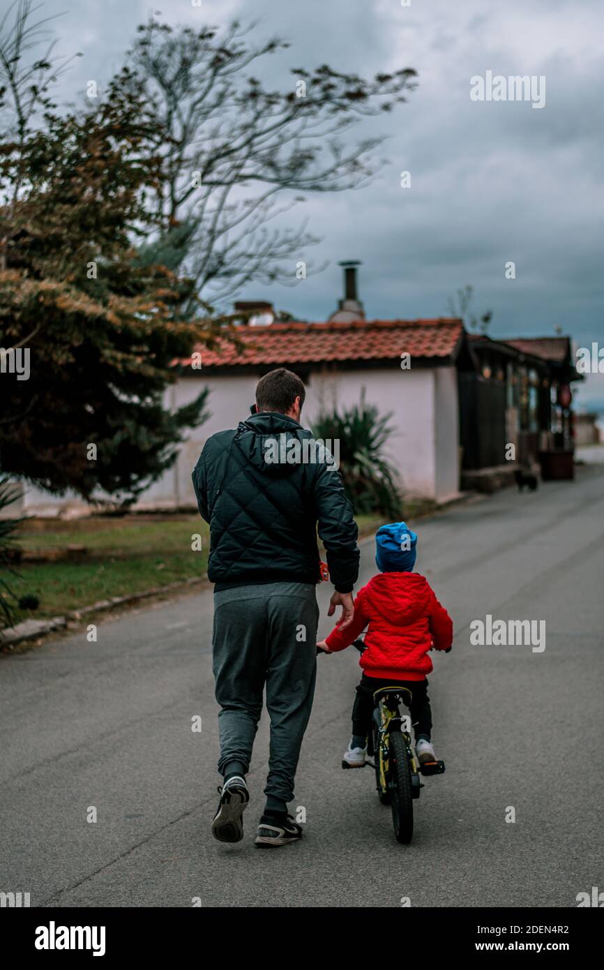 Un padre insegna al suo bambino come guidare una bicicletta. Lezioni di bicicletta. Foto Stock