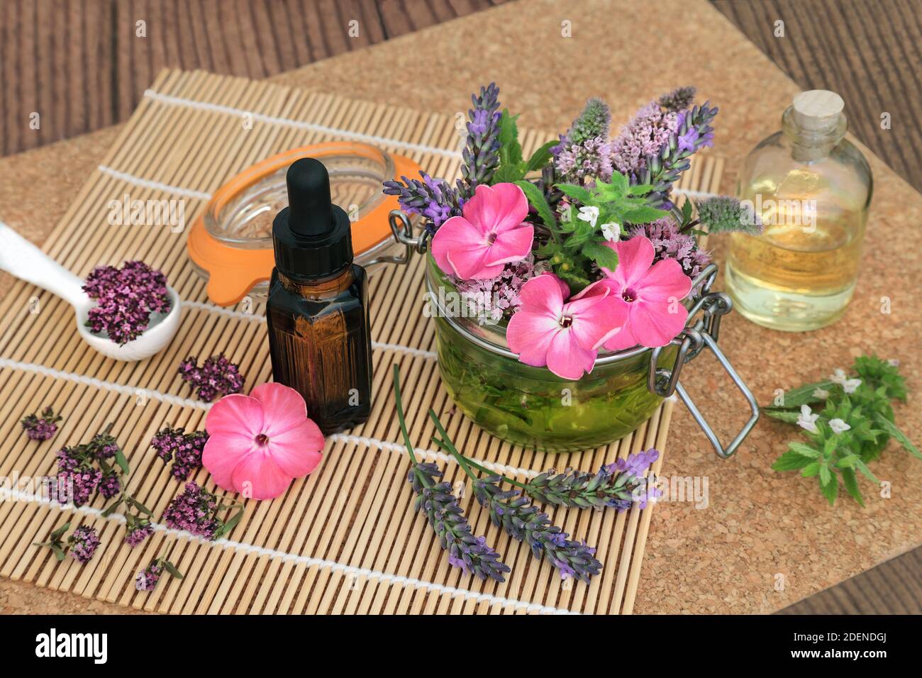Preparazione di olio essenziale per l'uso in aromaterapia e medicina naturale a base di erbe con fiori estivi, erbe, contagocce e bottiglie di olio. Assistenza sanitaria alternativa Foto Stock