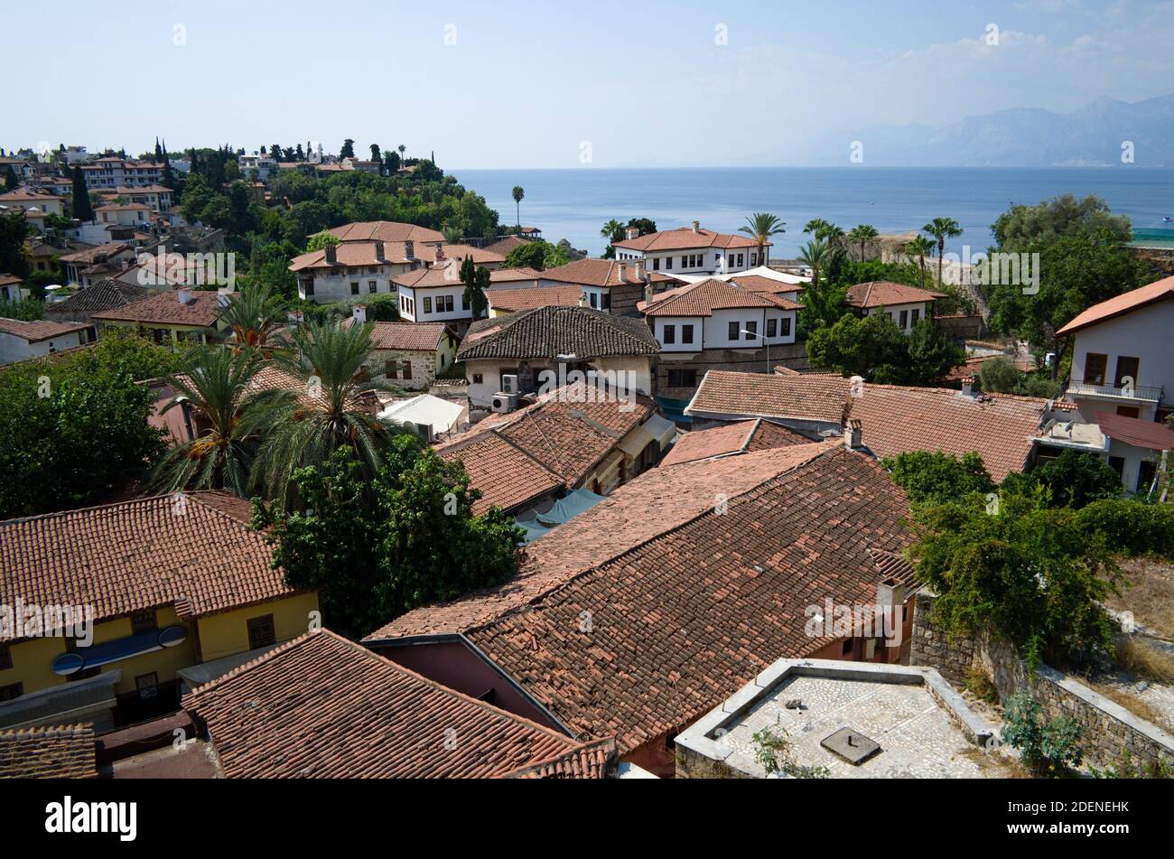 Vista panoramica sul centro storico, case con tetto in tegole arancioni. Mare e montagne sullo sfondo. Antalya, Turchia. Foto Stock