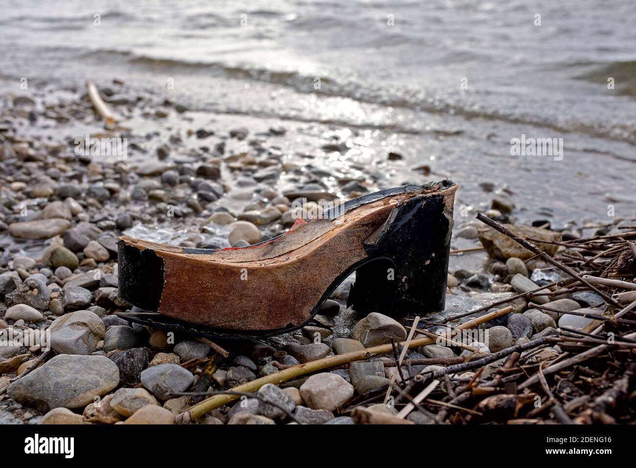 scarpa rotta di cui rimane solo la suola in legno, sdraiata sulla spiaggia Foto Stock