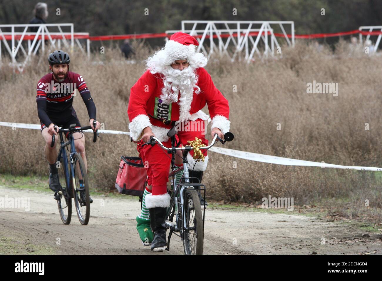 Babbo Natale a cavallo di una bicicletta che consegna regali con elfo helper. Foto Stock