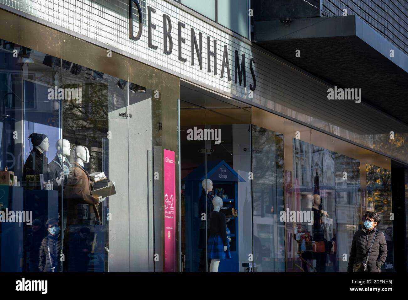 Gli acquirenti passano davanti al grande magazzino chiuso Debenhams di Oxford Street, a Londra, mentre il secondo blocco della pandemia di Coronavirus finisce, E un giorno prima che Londra entri nella restrizione Tier 2 quando i rivenditori saranno autorizzati a riaprire ancora una volta per il periodo di Natale, il 1 dicembre 2020, a Londra, Inghilterra. Si dice che 12,000 posti di lavoro siano a rischio dopo che le trattative finanziarie sono fallite il giorno dopo che Arcadia, proprietario di Topshop, è caduto nell'amministrazione. Foto Stock