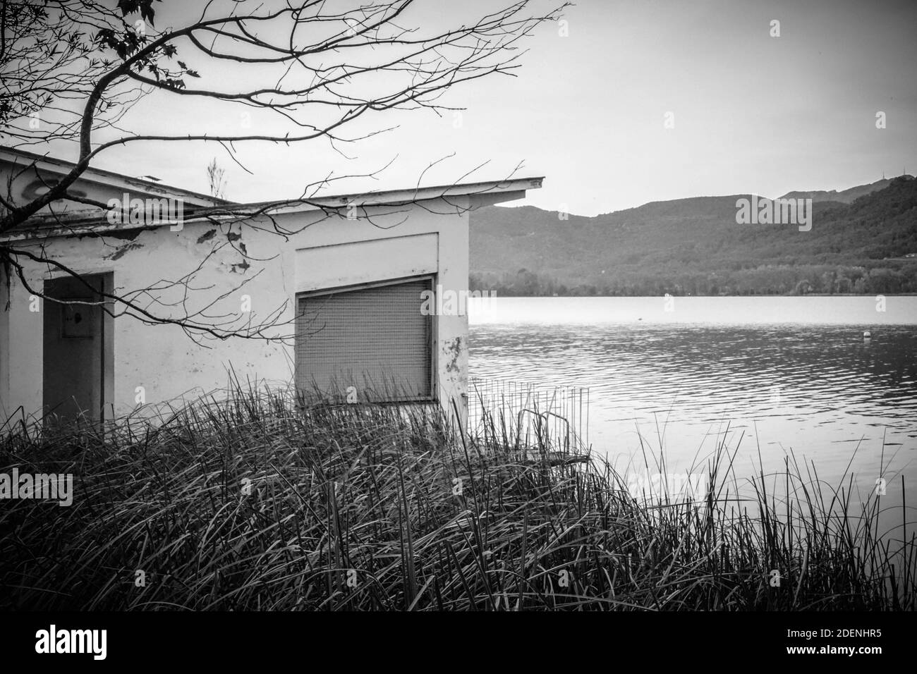 vecchia casa abbandonata vicino al lago con canne e montagne Foto Stock