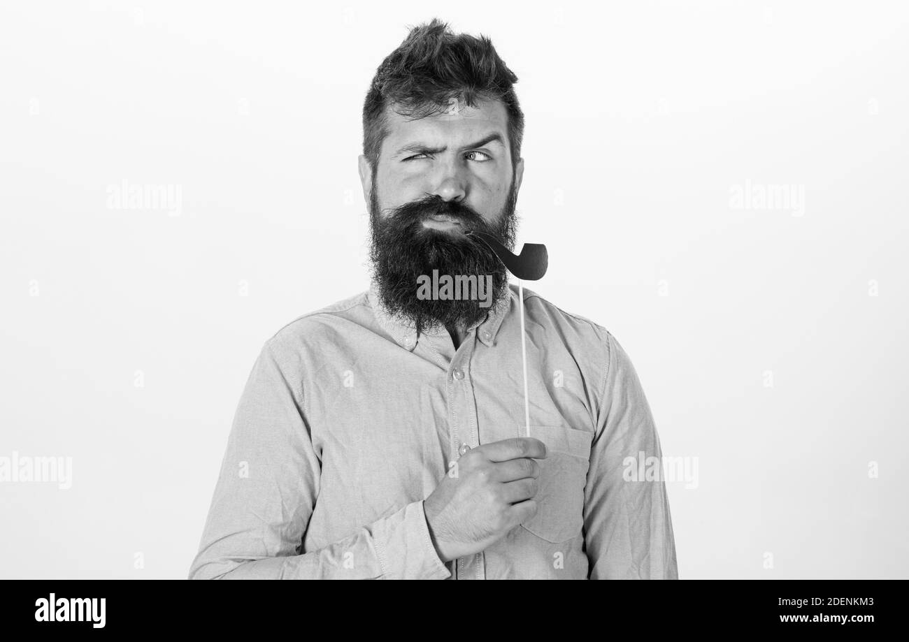Guy fuma il tubo di tabacco. Hipster con barba e baffi sul viso serio in posa con foto stand, spazio per la copia. Uomo che tiene la parte di carta props tubo di tabacco, sfondo bianco. Vecchio concetto di abitudini. Foto Stock