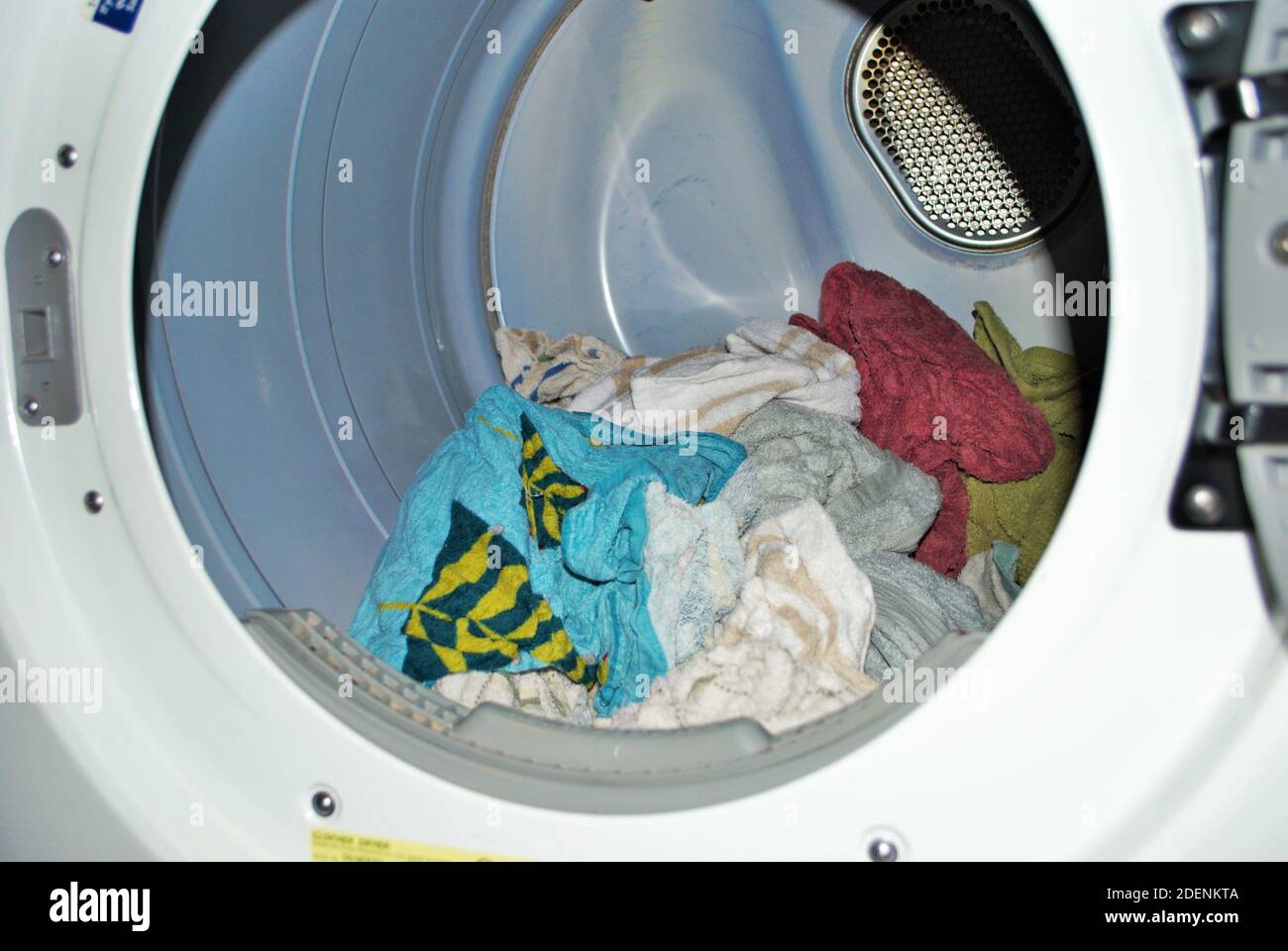 Carico di asciugamani bagnati che entrano nell'asciugatrice sulla lavanderia giorno Foto Stock