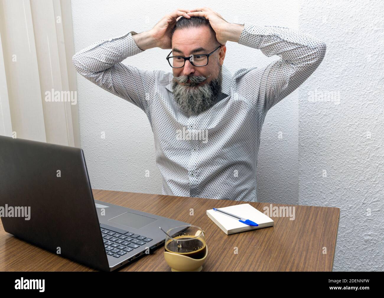 hipster lavora a casa utilizzando un computer portatile con mani sulla testa spaventato in shock con viso scioccato, eccitato da un'espressione spaventata Foto Stock