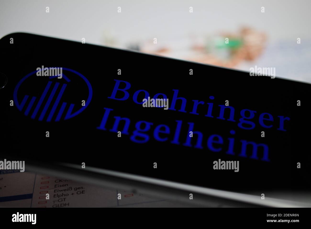 Viersen, Germania - 9 aprile. 2020: Primo piano dello schermo del telefono cellulare con la scritta del logo della società farmaceutica Boehringer Ingelheim, pillole sfocate An Foto Stock