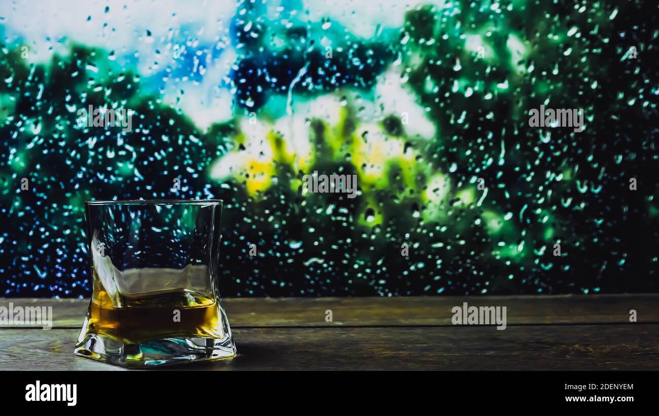 Un bicchiere di whisky sullo sfondo della pioggia fuori dalla finestra, sbattere sul bar vicino alla finestra in gocce. Foto Stock