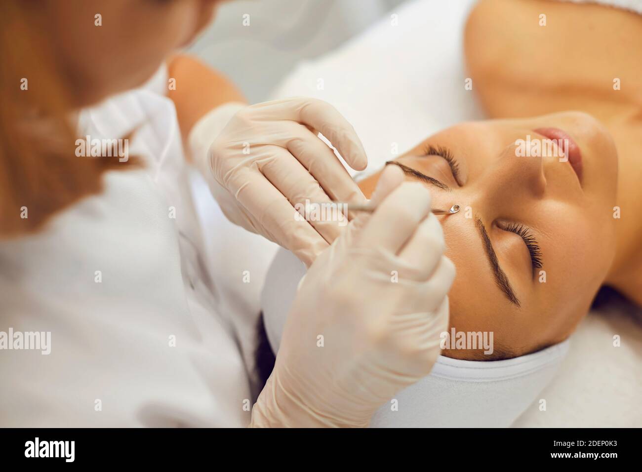 Cosmetologo professionista che rimuove i blackheads sulla faccia del cliente con l'aiuto dell'attrezzo speciale Foto Stock