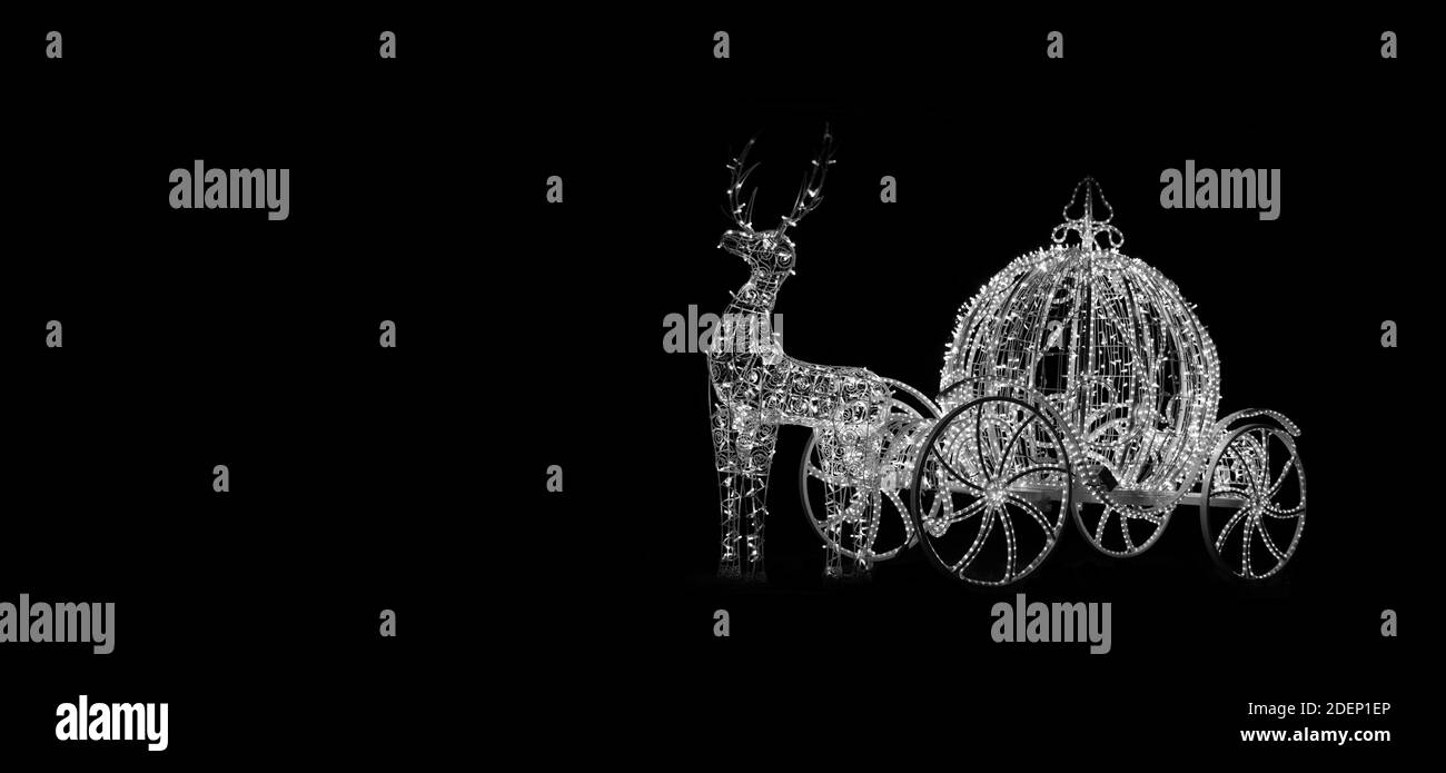 Silhouette di cervo e carrozza su sfondo nero sotto forma di luci di Natale. Banner o cartolina Foto Stock
