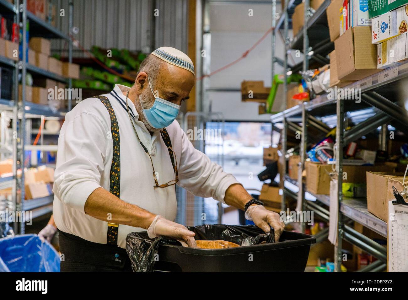 Un volontario che indossa una maschera prepara i pasti alla Chasdei Kaduri Jewish Food Bank.IT è l'unica organizzazione ebraica che è pienamente gestita da volontari, dedicata a fornire settimanalmente cibo non deperibile, prodotti da forno freschi e prodotti a centinaia di famiglie ebree bisognose nella zona di Toronto. Dalla pandemia di covid-19 nel marzo 2020, la domanda per il loro servizio è aumentata notevolmente. Foto Stock