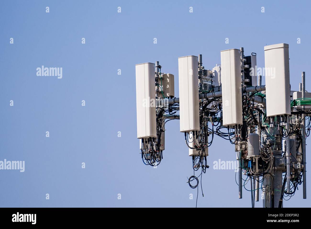 Primo piano della torre del telefono cellulare per telecomunicazioni con antenne di comunicazione wireless; sfondo blu e spazio di copia sulla destra Foto Stock