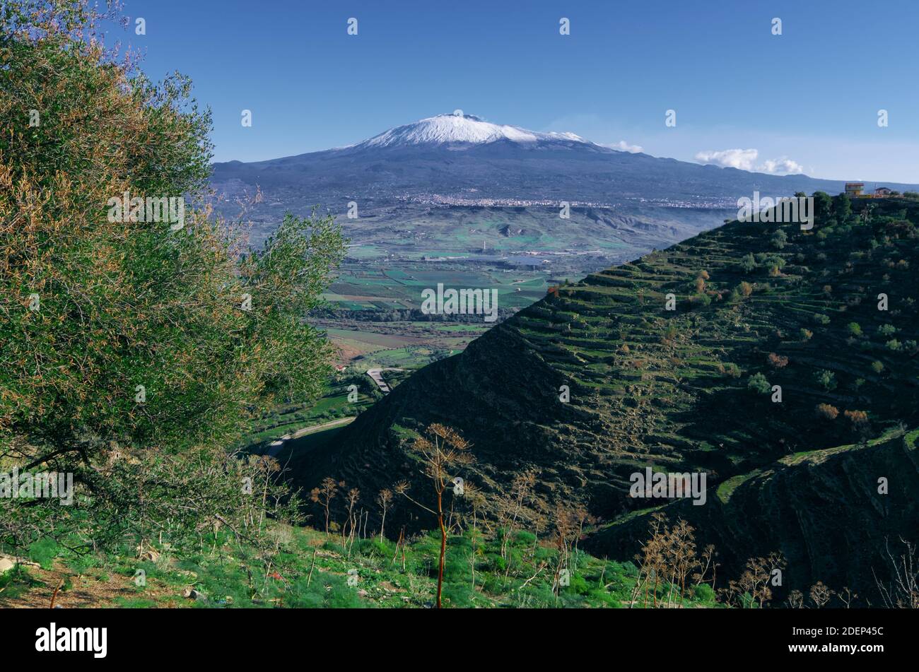 Vista su un abbandonato pendio terrazzato e sul versante sud-ovest dell'Etna, un punto di riferimento nel paesaggio siciliano Foto Stock