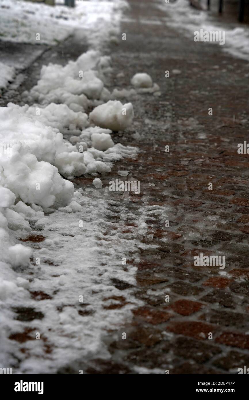 Un marciapiede in inverno con la festa della neve liberata. Il terreno viene trattato con sale per evitare condizioni scivolose. Esempio di manutenzione stagionale. Foto Stock