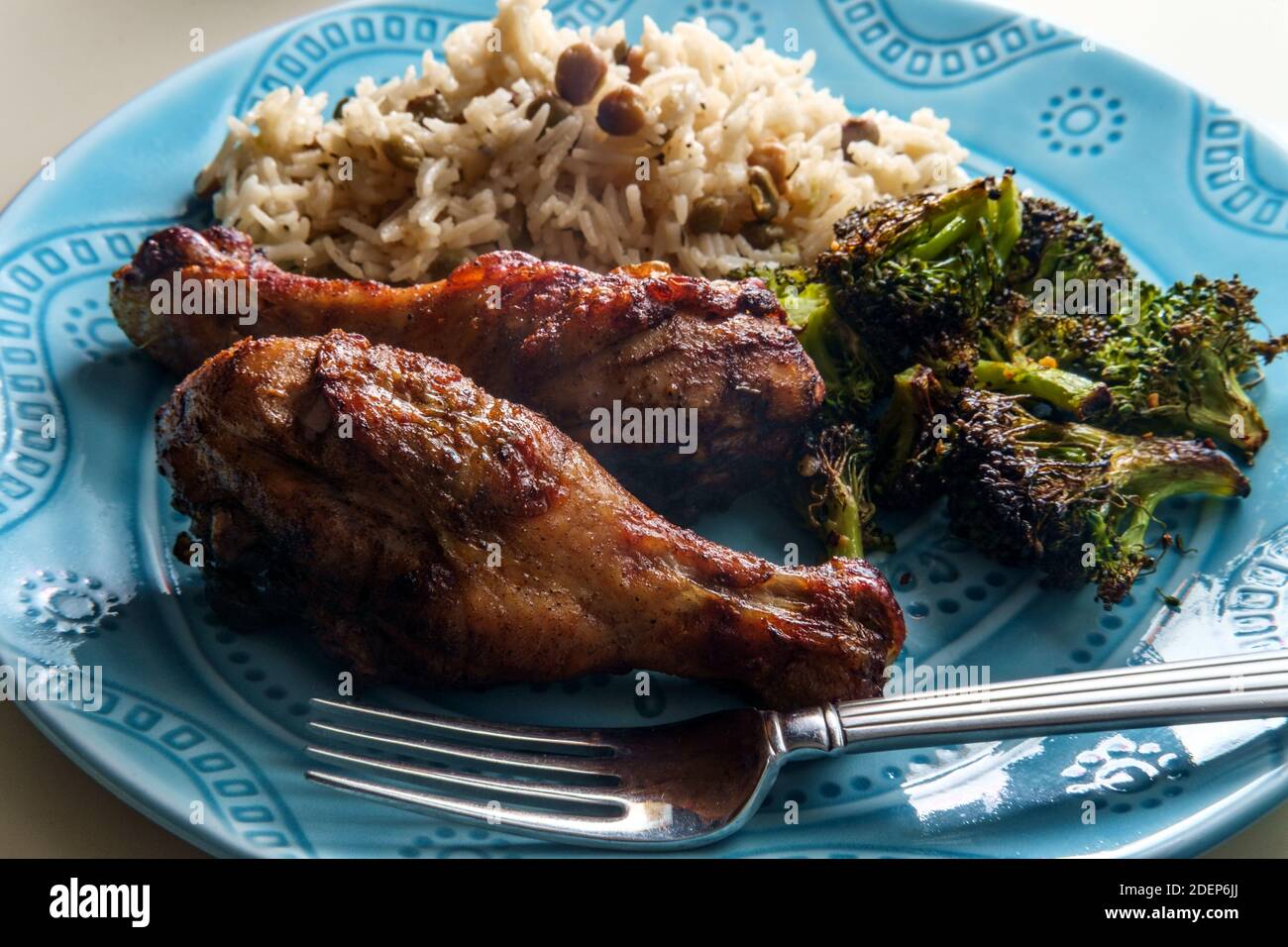 Autentiche e speziate gambe di pollo giamaicano a jerk servite con riso al cocco e piselli di piccione Foto Stock
