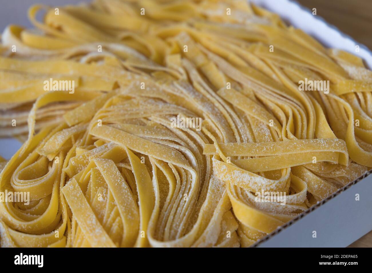 primo piano di una porzione di spaghetti freschi e crudi fatti in casa un cartone aperto Foto Stock