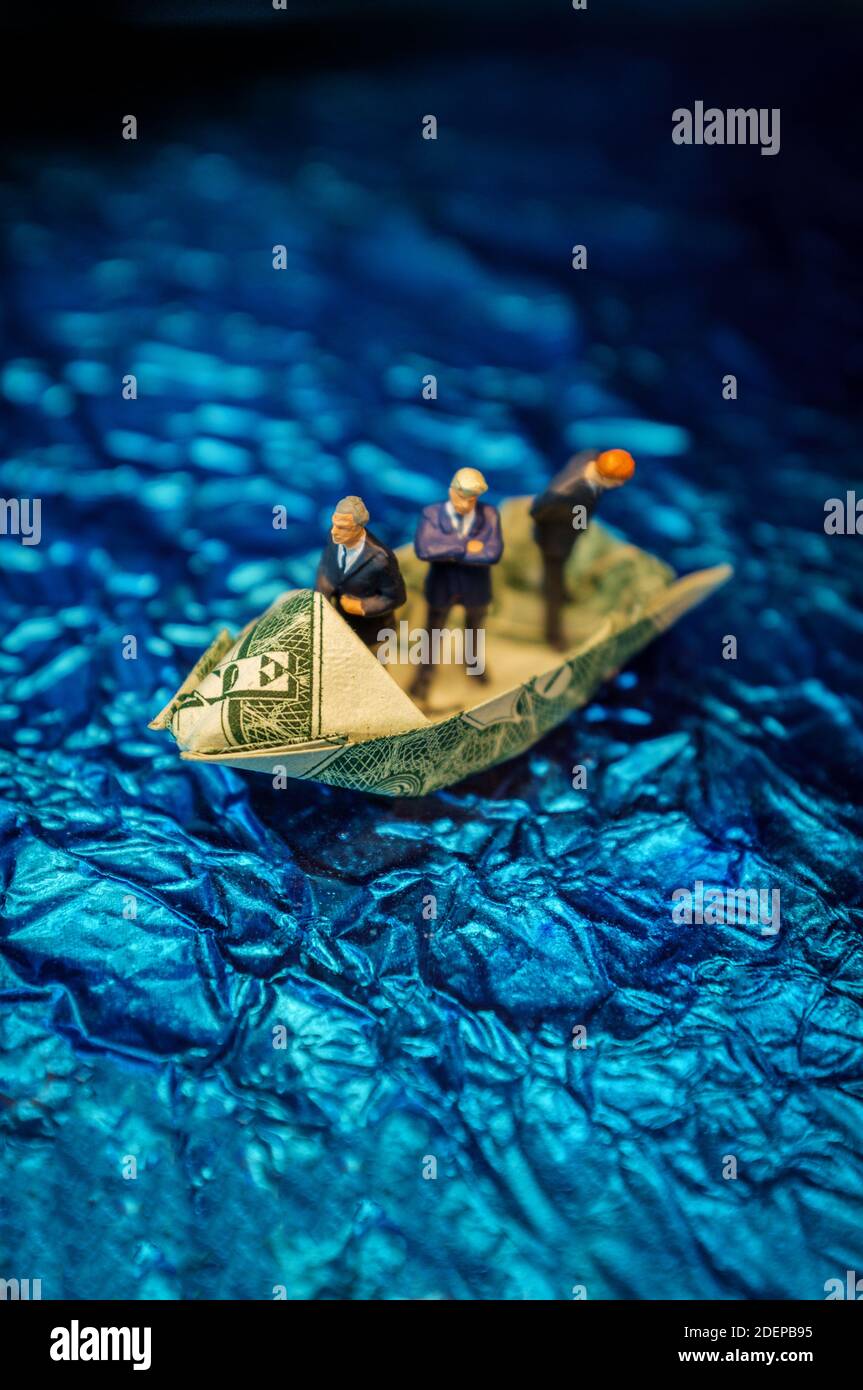 Miniatura imprenditori di figurine di giro sul dollaro origami yacht Foto Stock