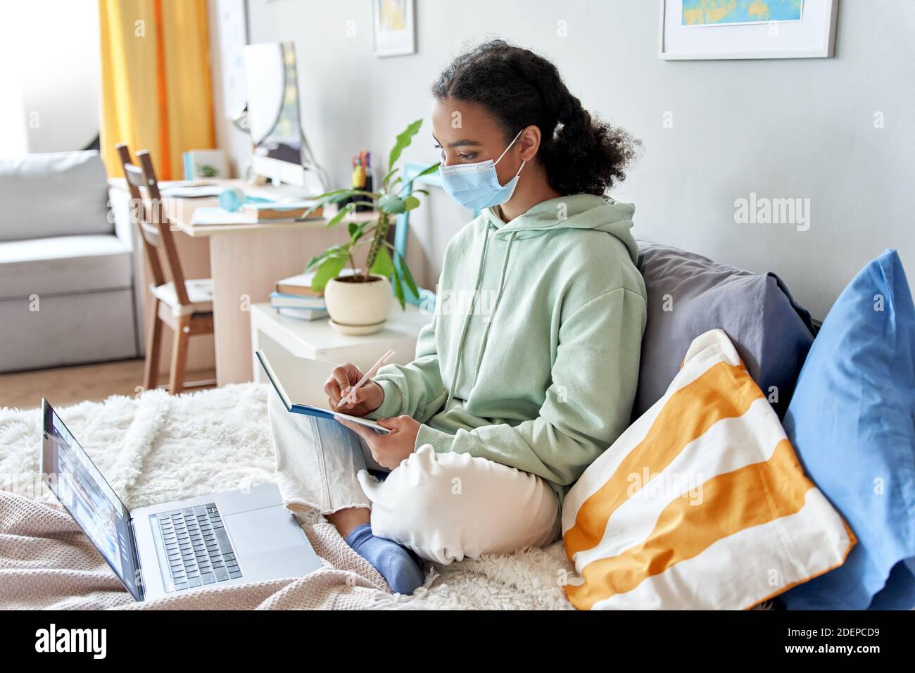 African american teen girl indossare maschera di distanza di apprendimento on-line a casa. Foto Stock