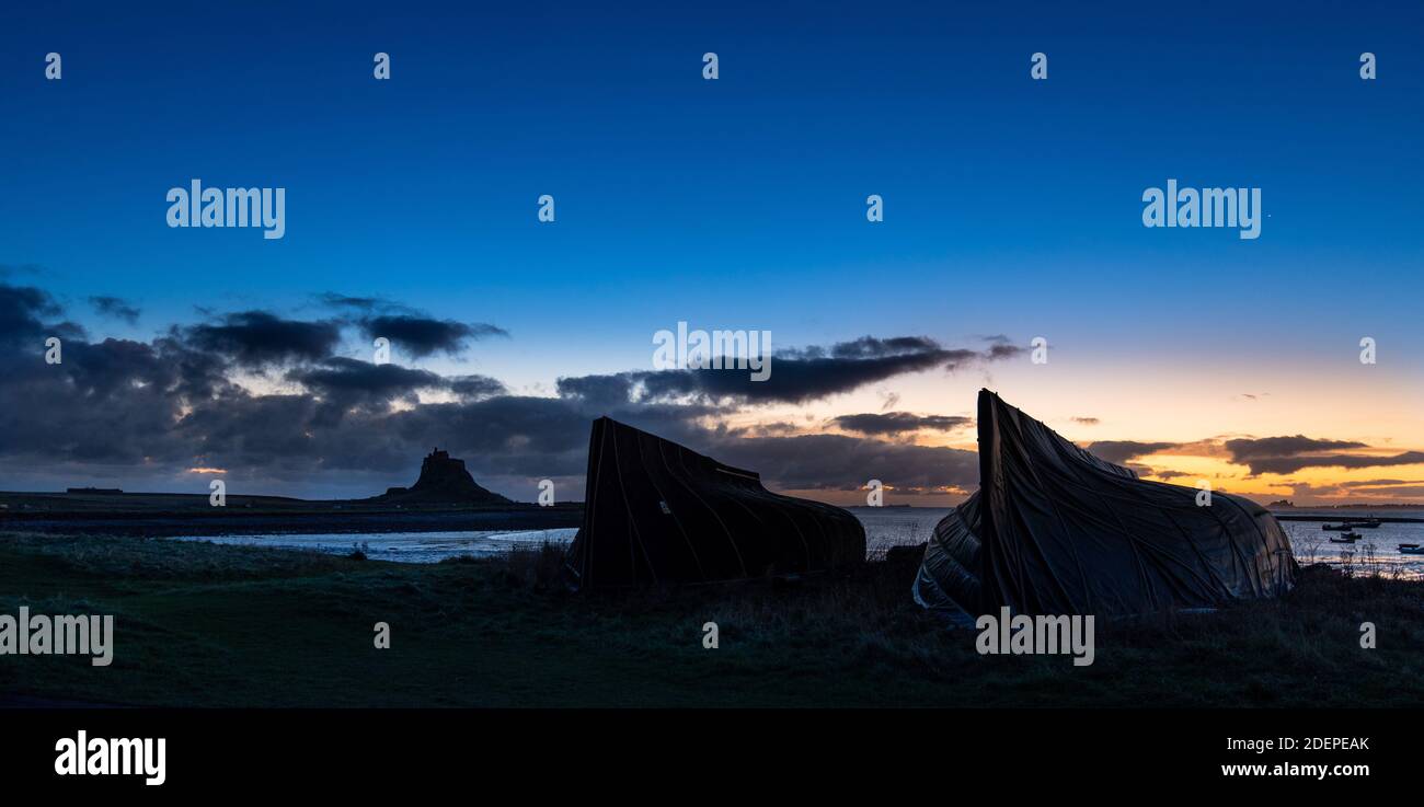 Le barche di aringhe scannano all'alba sull'Isola Santa di Lindisfarne con il suo castello Tudor sul affioramento che domina il porto. Lindisfarne, Inghilterra Foto Stock