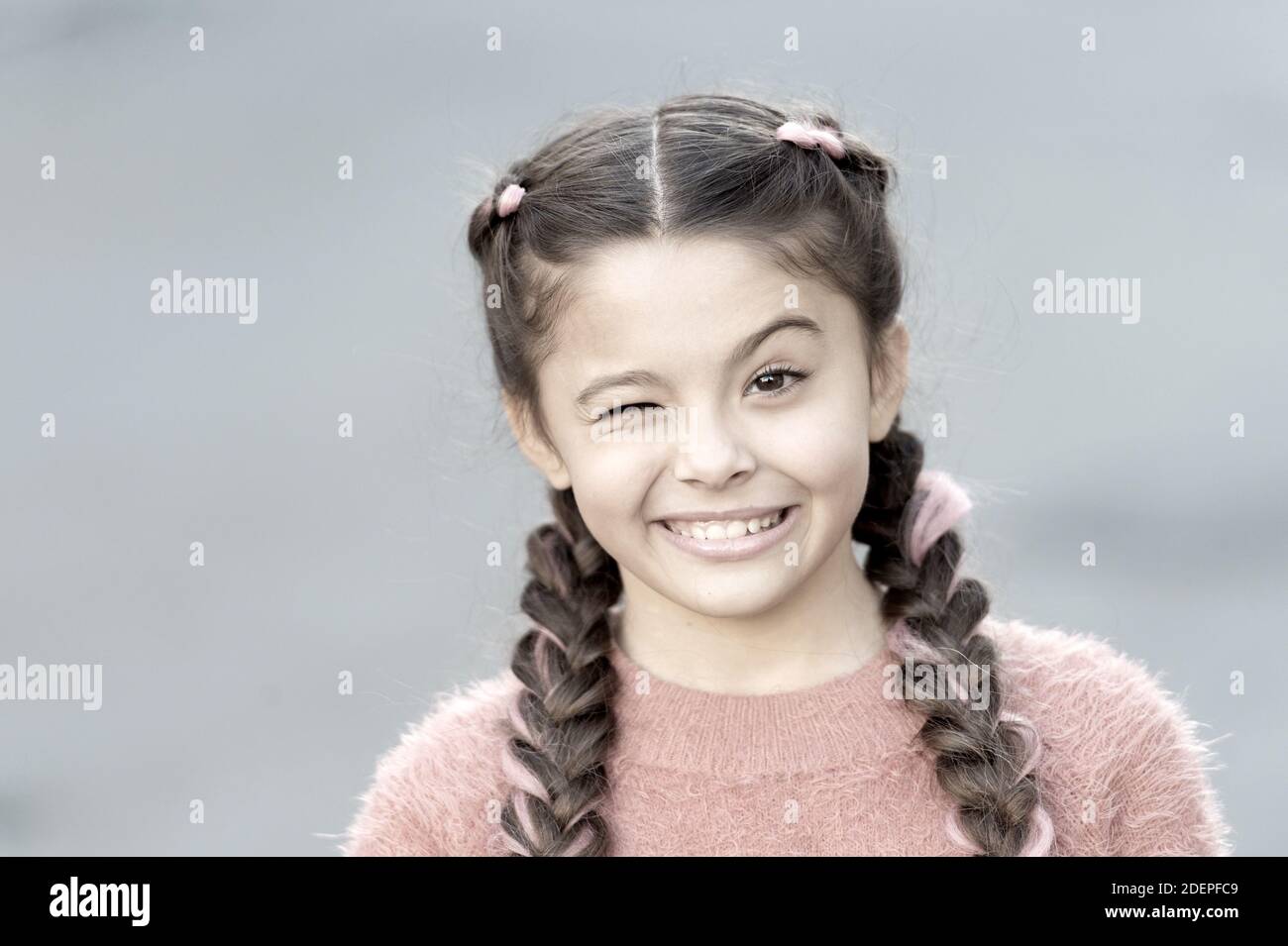 Fingere e scherzando. Giocoso bambino allegro espressione. Cose che andrà bene. Wink ragazza volto allegro sfondo grigio. Kid ragazza allegro soddisfatti di tutto. Buon umore emozioni positive. Foto Stock