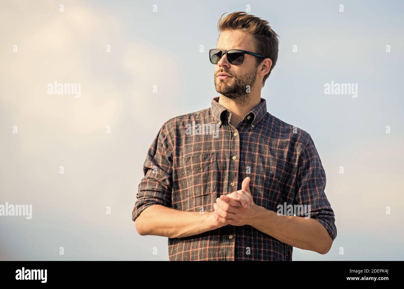 Occhiali da sole alla moda. Modello uomo occhiali esterni blu cielo sfondo. Concetto di protezione ultravioletta. Visione perfetta. Vedere chiaro. Bel ragazzo wea Foto Stock