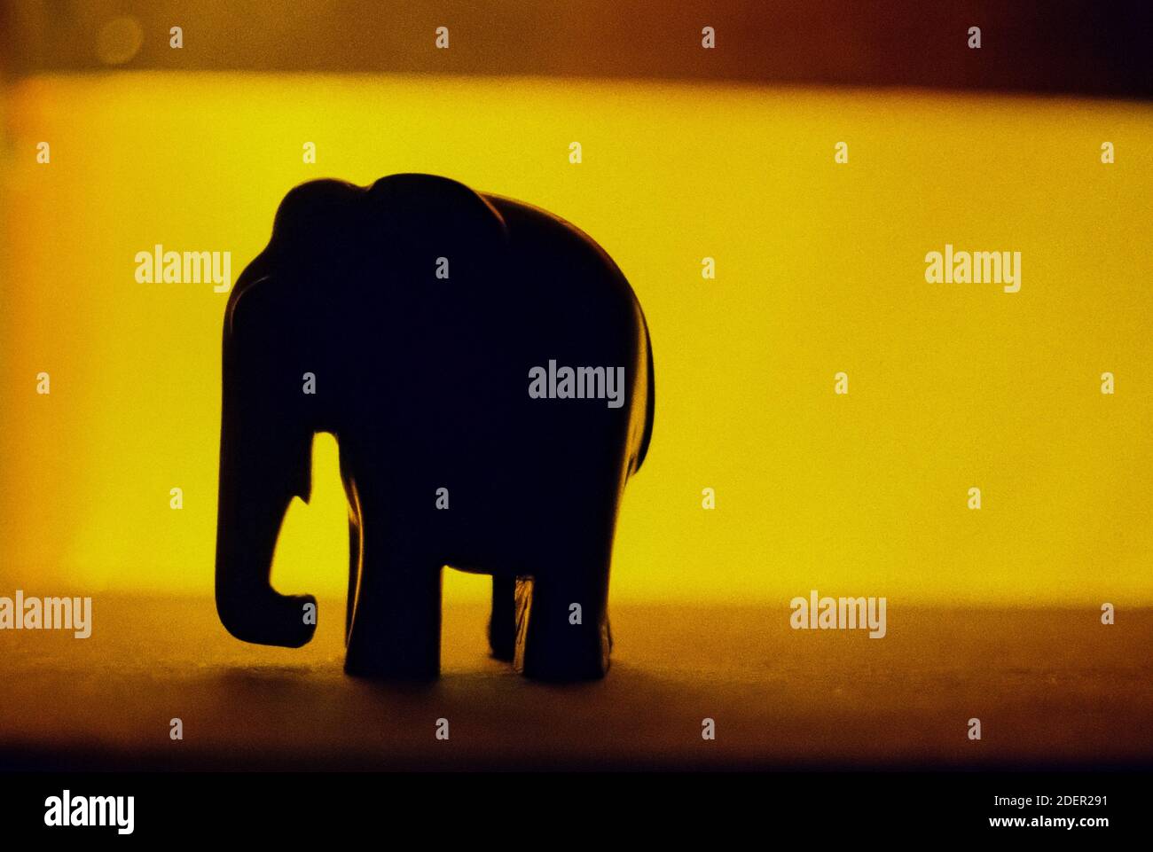 Un primo piano di una piccola statua di elefante su un sfondo giallo Foto Stock