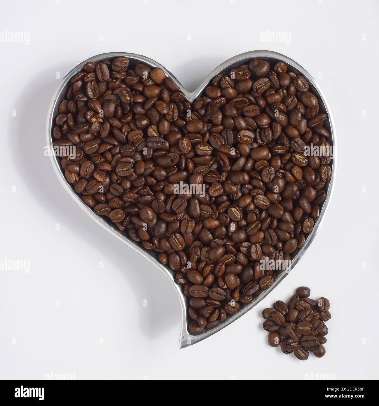 chicchi di caffè in un contenitore a forma di cuore Foto Stock