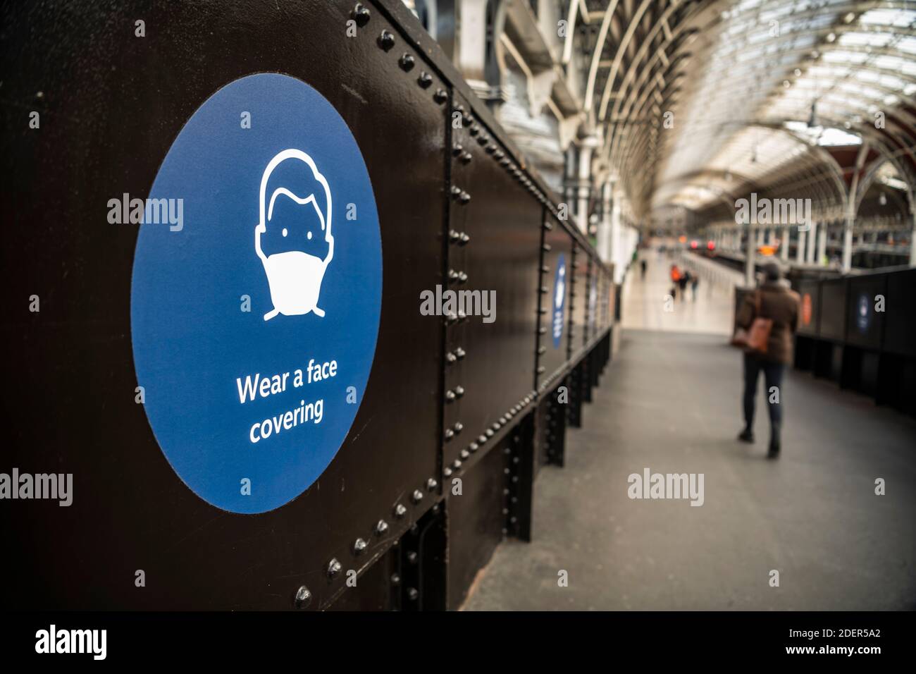 Il cartello informativo del Coronavirus Covid-19 recita indossa una maschera di copertura alla stazione ferroviaria di Paddington a Londra quando i mezzi di trasporto pubblico erano silenziosi e disertati, senza persone in Inghilterra, Europa Foto Stock