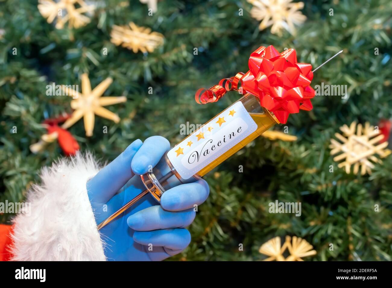 La mano di Babbo Natale con iniezione di vaccino, su uno sfondo le decorazioni di Natale. Foto Stock