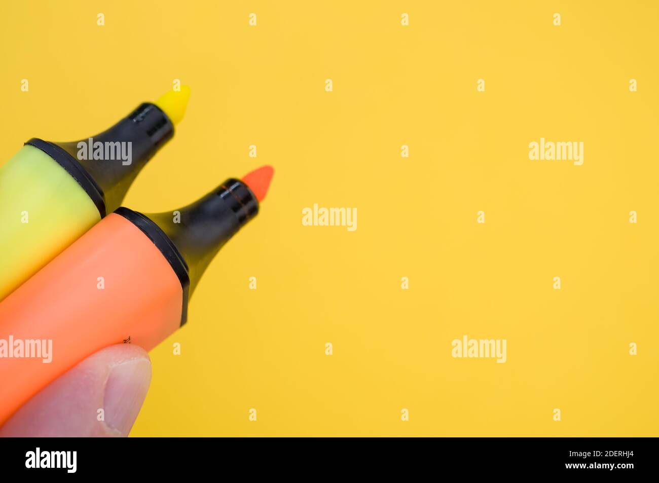 Un colpo di dita che tiene isolati due marcatori colorati uno sfondo luminoso ed Foto Stock