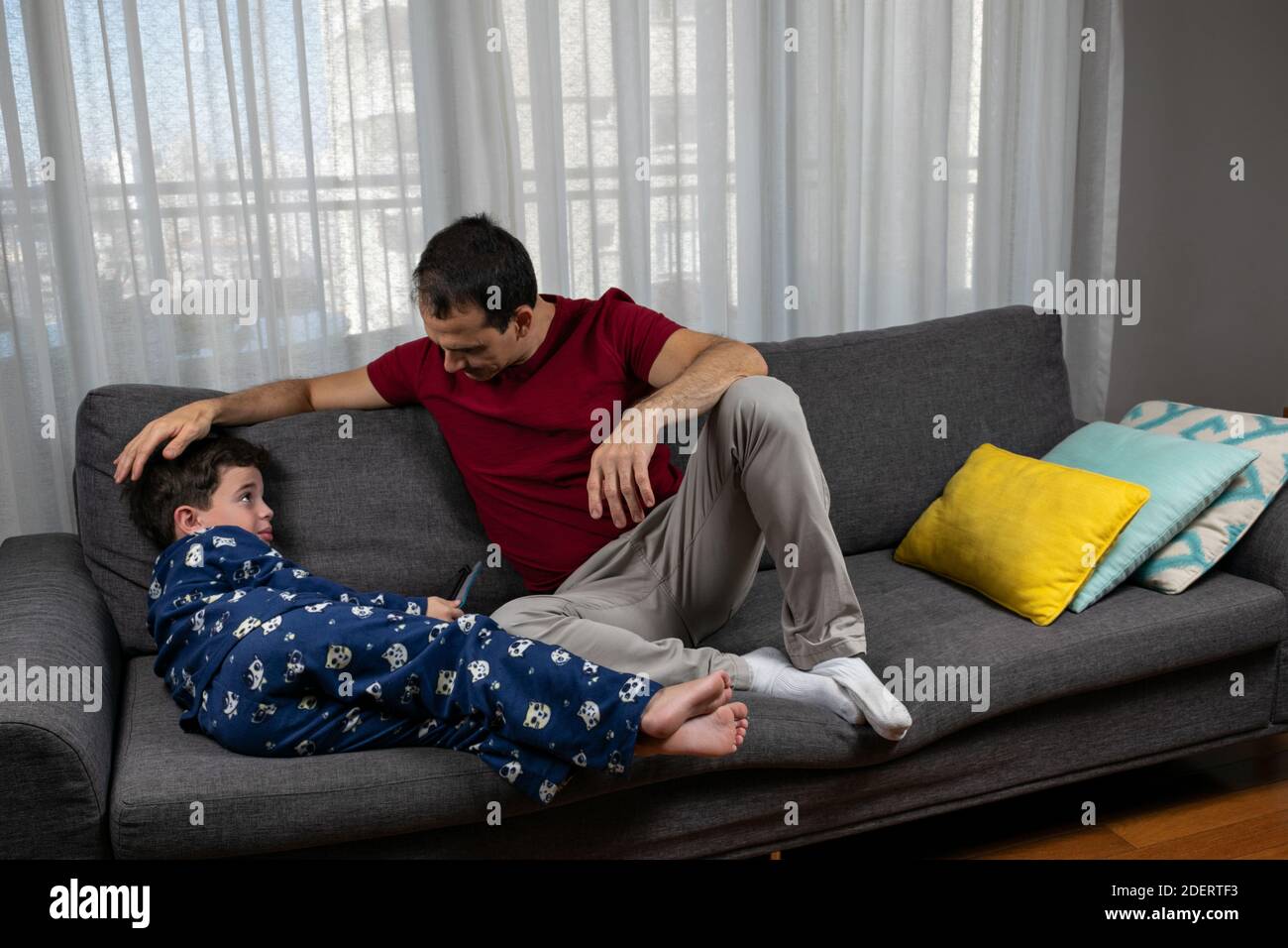 Uomo maturo (44 anni) seduto accanto al figlio (6 anni) e stromando la testa. Foto Stock