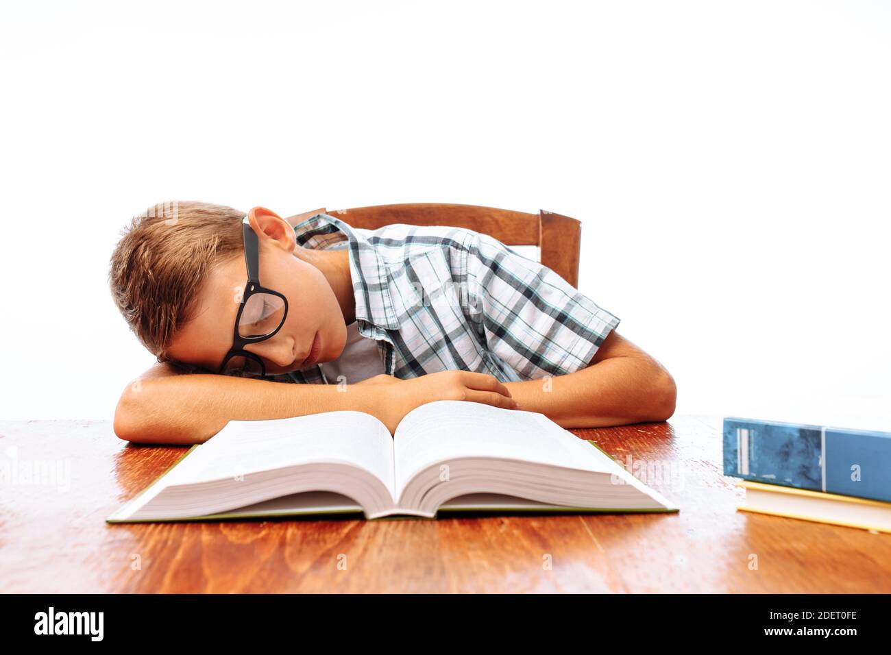 Teen guy si addormentò seduto con i libri, studente che dormiva alla scrivania in Studio Foto Stock