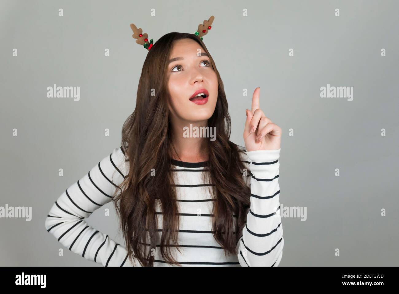 Una donna con le decorazioni di Natale nei suoi capelli sta pensando ad un'idea di festa. Foto di alta qualità Foto Stock