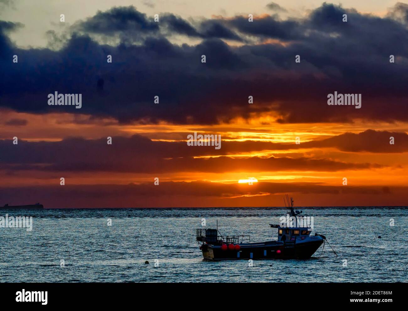 La barca da pesca all'ancora mentre il sole si accende Foto Stock