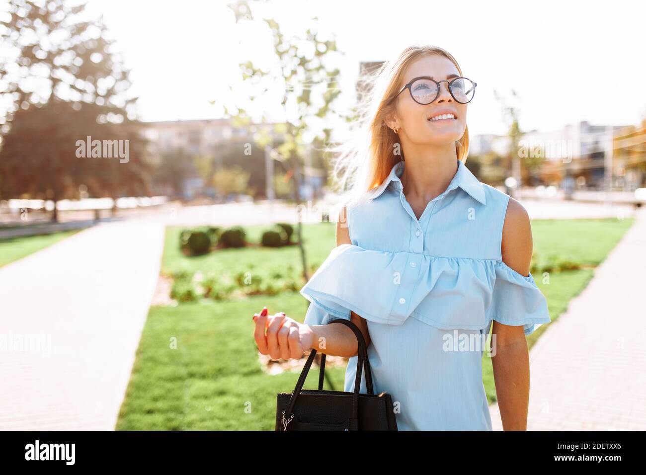 Giovane positiva bella ragazza con occhiali, studente che passeggiava nel Parco, di buon umore Foto Stock
