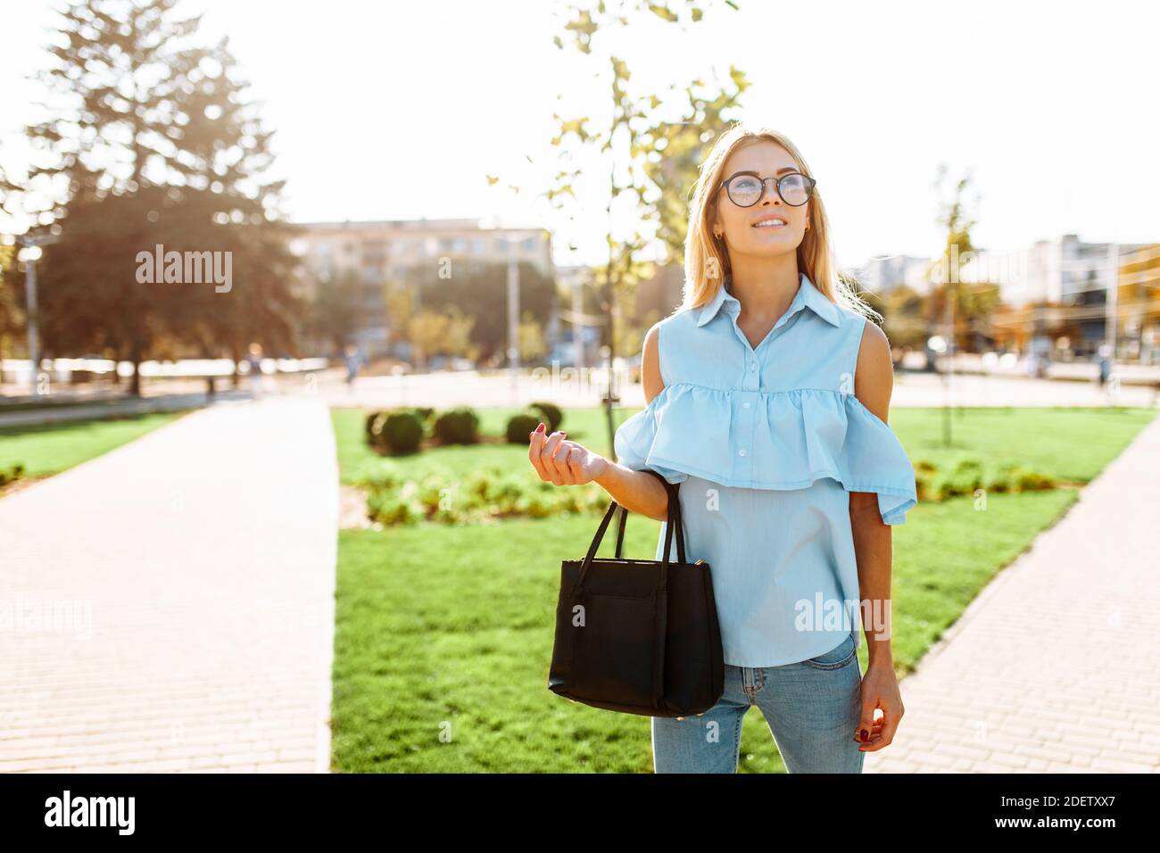 Giovane positiva bella ragazza con occhiali, studente che passeggiava nel Parco, di buon umore Foto Stock