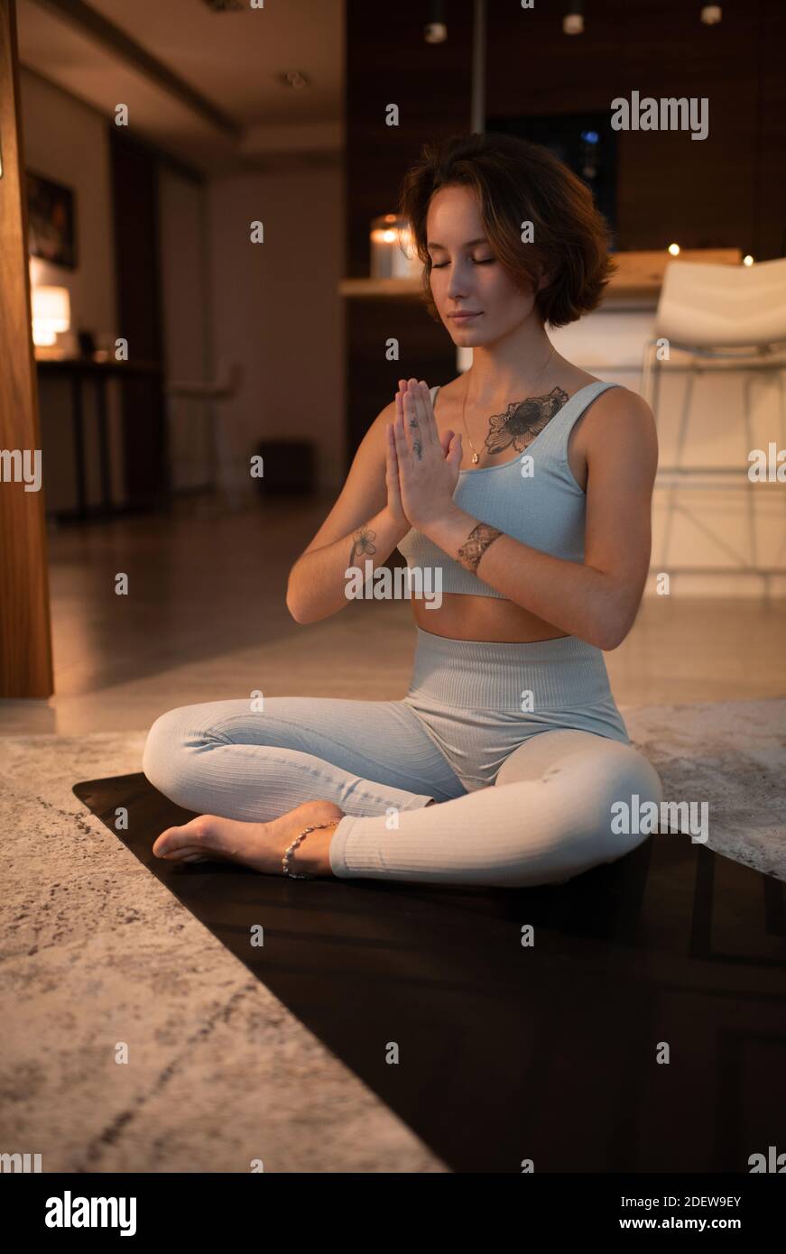 Sottile donna che gesturava namaste e chiude gli occhi mentre meditava dentro Posa Padmasana Foto Stock