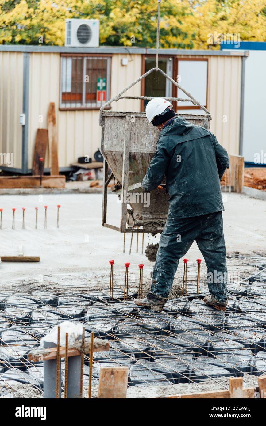 Il lavoratore di costruzione che utilizza le norme di sicurezza sta lavorando su un rinforzato calcestruzzo gettando calcestruzzo Foto Stock