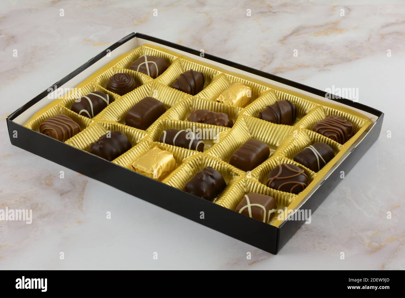 Scatola aperta di cioccolatini belgi assortiti in lamina color oro sul tavolo Foto Stock