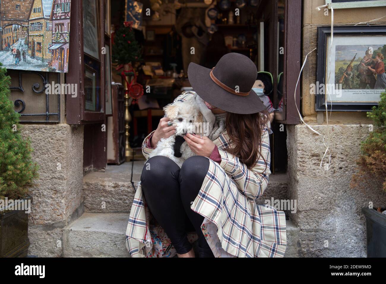 Una persona dai capelli lunghi che gioca con un adorabile cucciolo seduto su un gradino Foto Stock