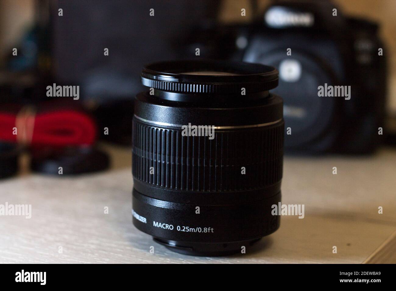 Obiettivo sul tavolo e una fotocamera sullo sfondo Foto Stock