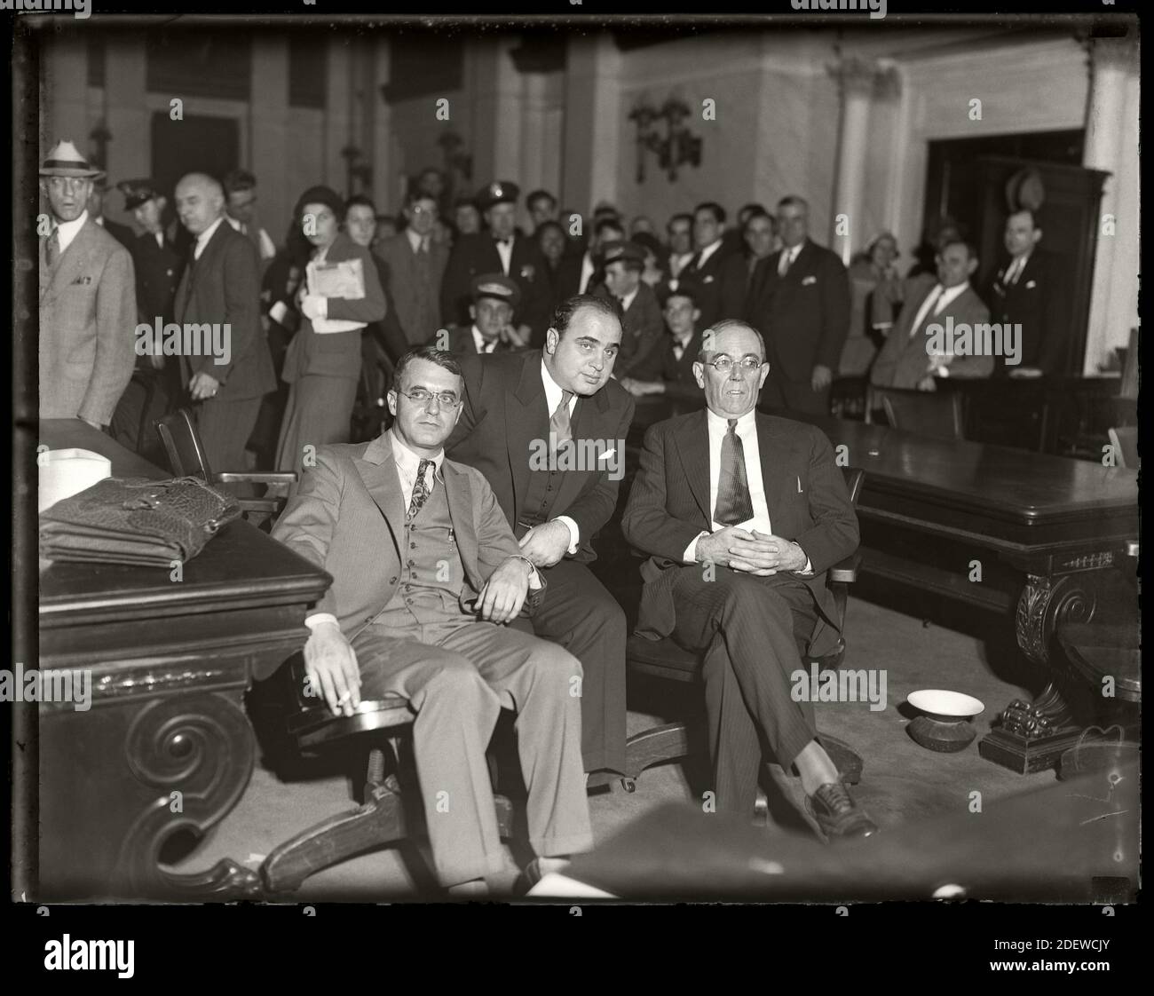 Al Capone siede in tribunale federale durante il processo di evasione fiscale con i suoi avvocati Michael Ahern, a sinistra, e Albert Fink, a destra. Chicago, Illinois, 7 ottobre 1931. Immagine da negativo vetro 4x5 pollici. Foto Stock
