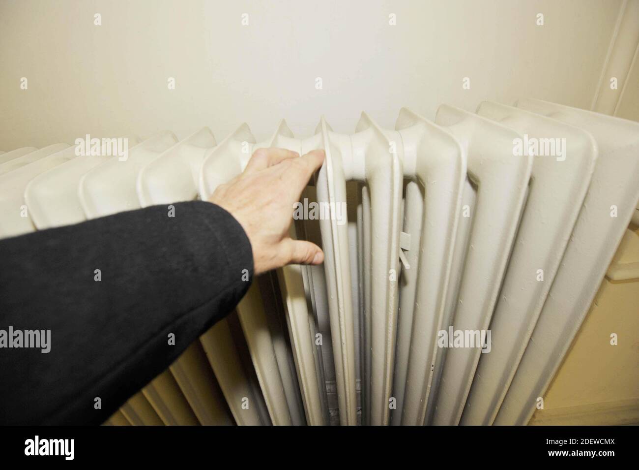 persona che tocca il radiatore in una stanza, riscaldamento convettore per stanze di riscaldamento Foto Stock