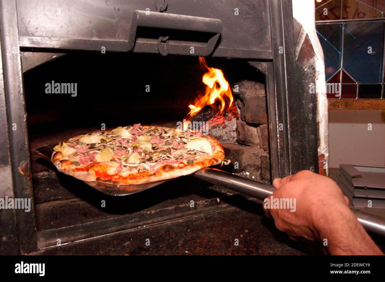 lo chef pizzeria infila la pizza nel forno a legna caldo Foto Stock